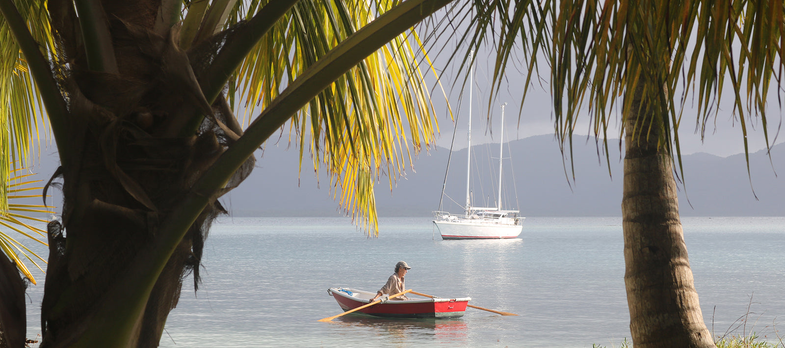 small red boat in front of a large sailboat